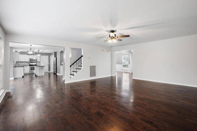 unfurnished living room with ceiling fan with notable chandelier and dark hardwood / wood-style flooring