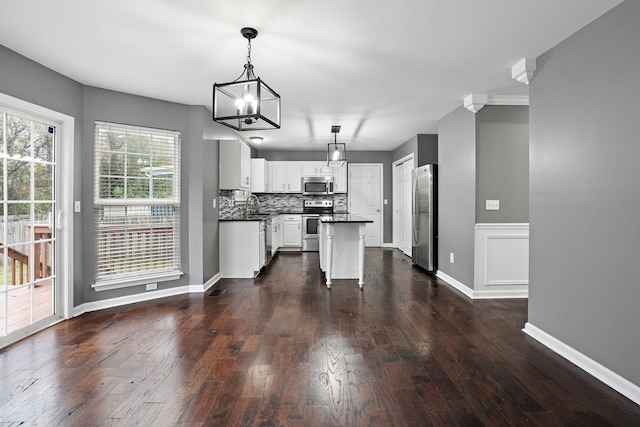 kitchen with dark hardwood / wood-style flooring, stainless steel appliances, sink, pendant lighting, and a center island