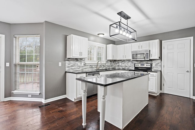 kitchen featuring a kitchen island, dark hardwood / wood-style flooring, decorative light fixtures, white cabinets, and appliances with stainless steel finishes