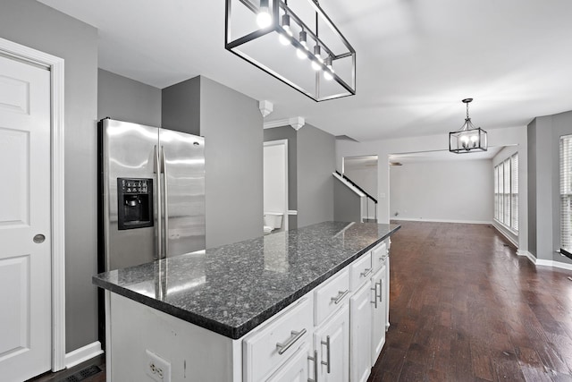 kitchen with dark wood-type flooring, white cabinets, hanging light fixtures, dark stone countertops, and a kitchen island