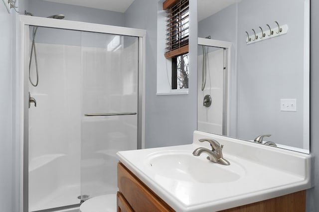 bathroom with vanity, a shower with shower door, and toilet