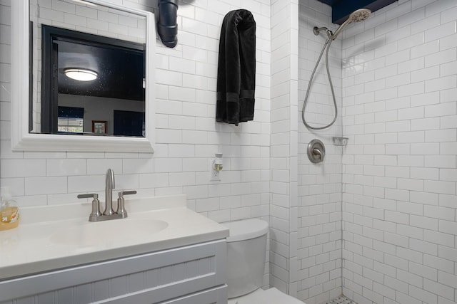 bathroom with tiled shower, vanity, tasteful backsplash, and toilet