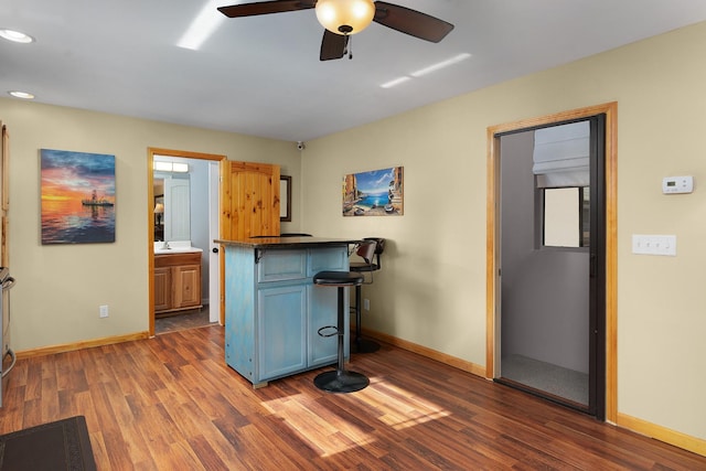 kitchen featuring kitchen peninsula, dark hardwood / wood-style floors, ceiling fan, and a breakfast bar area