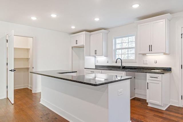 kitchen with a center island, hardwood / wood-style flooring, white cabinetry, and sink