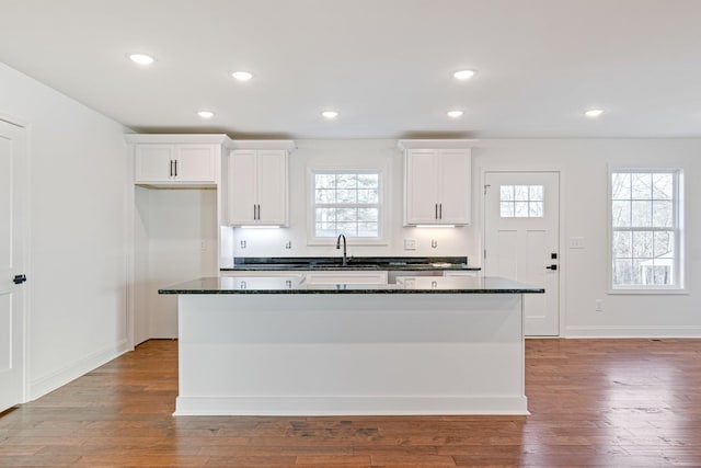 kitchen with white cabinets, a kitchen island, and dark stone countertops