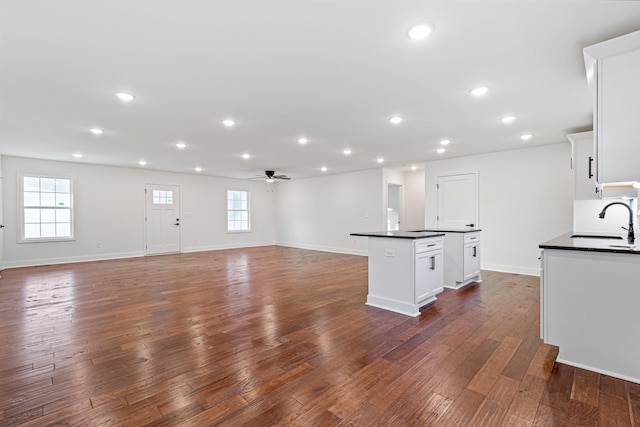 kitchen featuring ceiling fan, sink, a kitchen island, dark hardwood / wood-style floors, and white cabinets