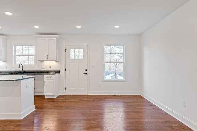 kitchen with dark stone countertops, white cabinetry, sink, and dark hardwood / wood-style floors