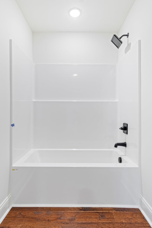 bathroom featuring hardwood / wood-style flooring and washtub / shower combination