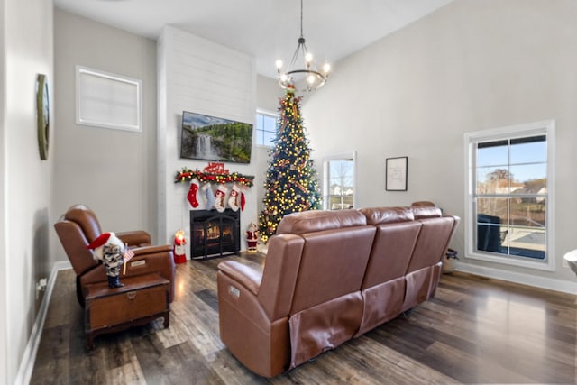 living room with a large fireplace, dark wood-type flooring, and a notable chandelier