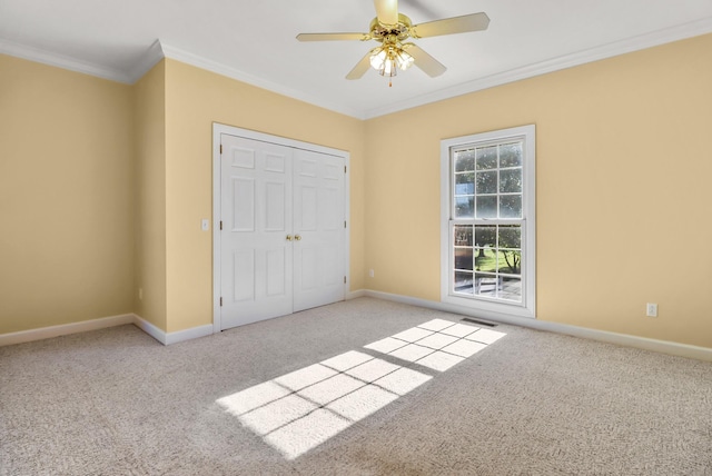 unfurnished bedroom with a closet, ceiling fan, crown molding, and light colored carpet