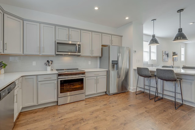 kitchen with backsplash, stainless steel appliances, light hardwood / wood-style floors, and gray cabinetry