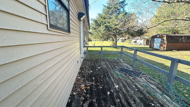 wooden terrace featuring a lawn and a storage shed