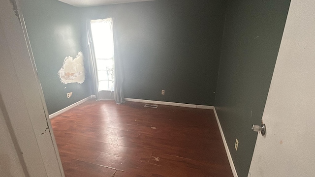 spare room with dark hardwood / wood-style flooring and a wealth of natural light