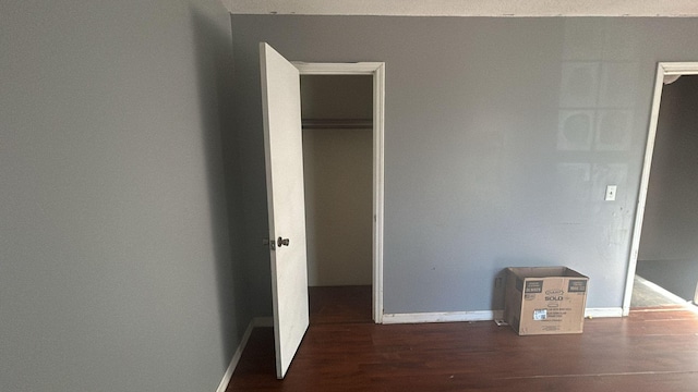 unfurnished bedroom with dark hardwood / wood-style flooring and a closet