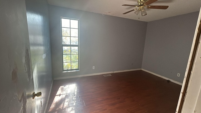 empty room with ceiling fan, dark wood-type flooring, and a wealth of natural light