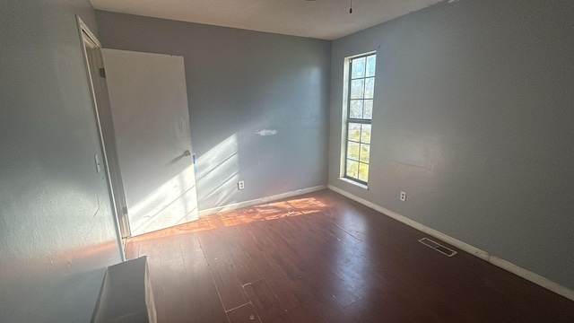 empty room featuring dark hardwood / wood-style flooring and plenty of natural light