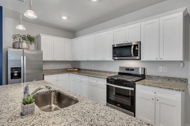 kitchen featuring white cabinetry, sink, decorative light fixtures, and appliances with stainless steel finishes