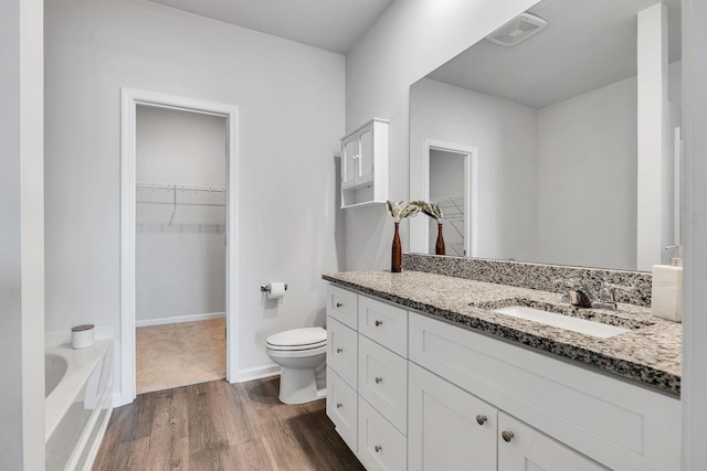 bathroom featuring a bath, vanity, wood-type flooring, and toilet