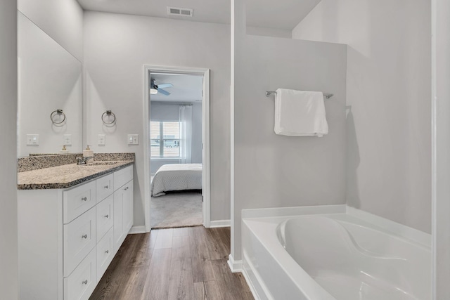 bathroom featuring hardwood / wood-style flooring, vanity, ceiling fan, and a washtub