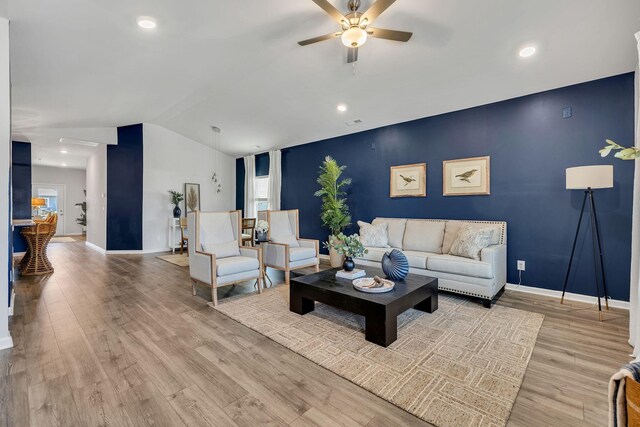 living room featuring lofted ceiling, ceiling fan, and light wood-type flooring