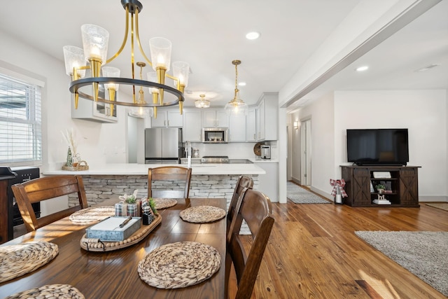 dining room with sink, light hardwood / wood-style flooring, and a notable chandelier