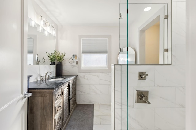 bathroom featuring a shower, vanity, and tile walls