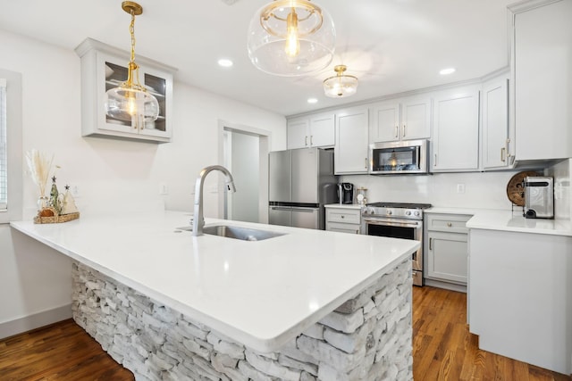 kitchen with kitchen peninsula, stainless steel appliances, hanging light fixtures, and sink