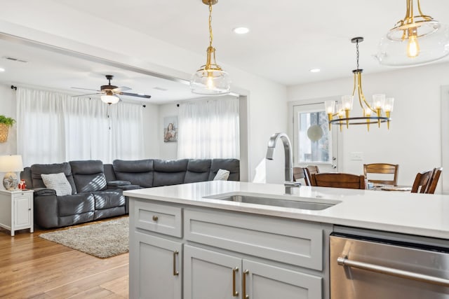 kitchen featuring pendant lighting, dishwasher, ceiling fan with notable chandelier, sink, and light hardwood / wood-style floors