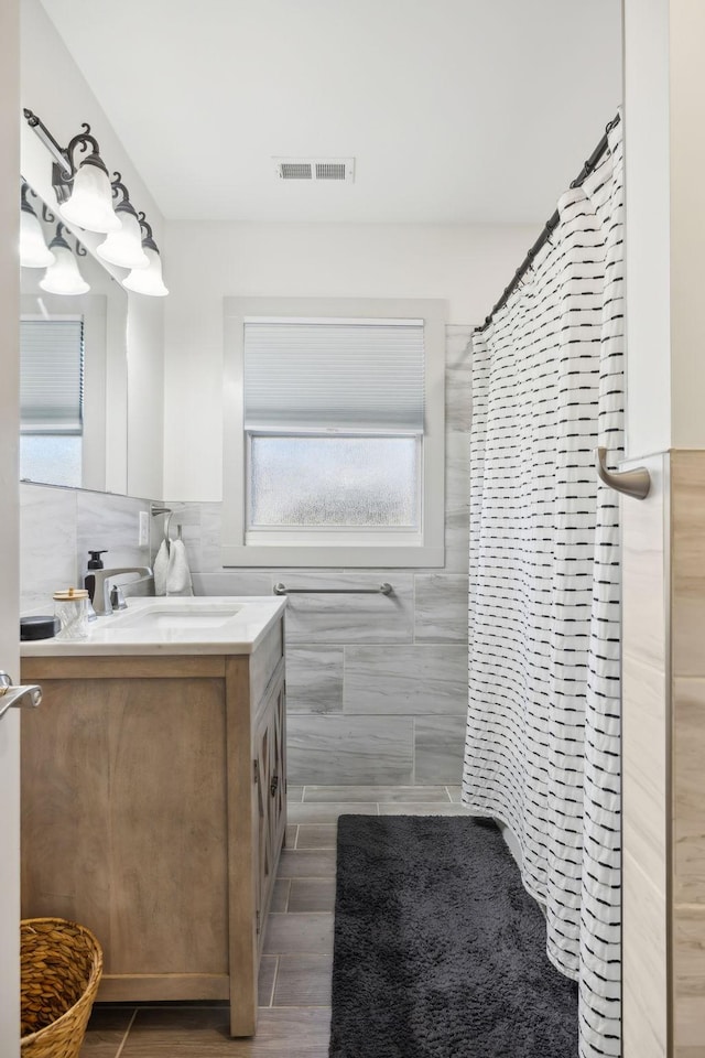 bathroom with vanity, curtained shower, and tile walls