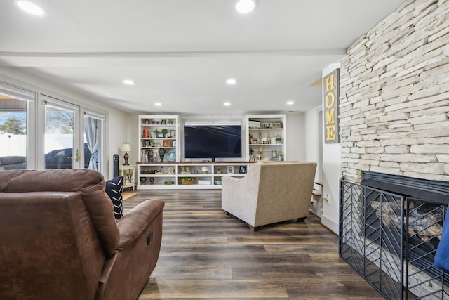 living room with a stone fireplace and dark wood-type flooring