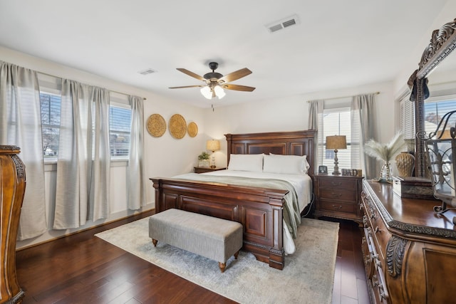 bedroom featuring dark hardwood / wood-style floors, multiple windows, and ceiling fan