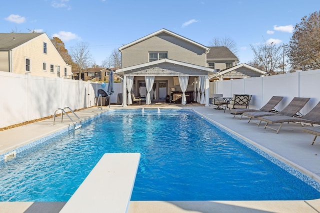 view of swimming pool with a patio and a diving board