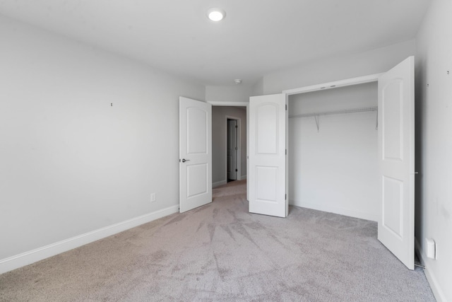 unfurnished bedroom featuring light carpet and a closet