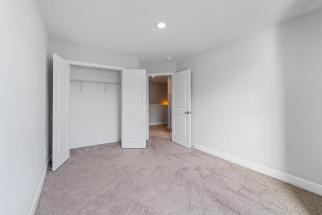 unfurnished bedroom with light carpet and a closet