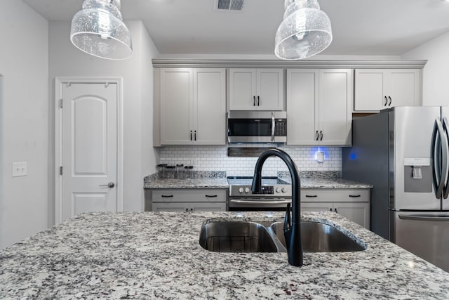 kitchen with pendant lighting, decorative backsplash, gray cabinets, and stainless steel appliances