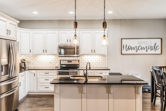 kitchen with sink, a breakfast bar area, white cabinets, stainless steel appliances, and a center island with sink