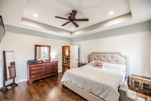 bedroom featuring dark hardwood / wood-style floors, a raised ceiling, and ceiling fan