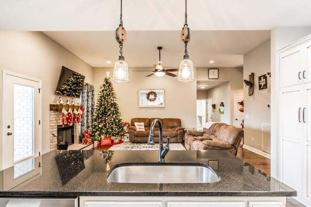 kitchen featuring pendant lighting, white cabinetry, sink, and a center island with sink