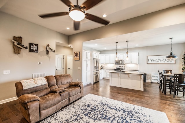 living room featuring ceiling fan, dark hardwood / wood-style floors, and sink