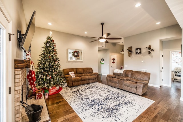 living room with a fireplace, dark wood-type flooring, and ceiling fan