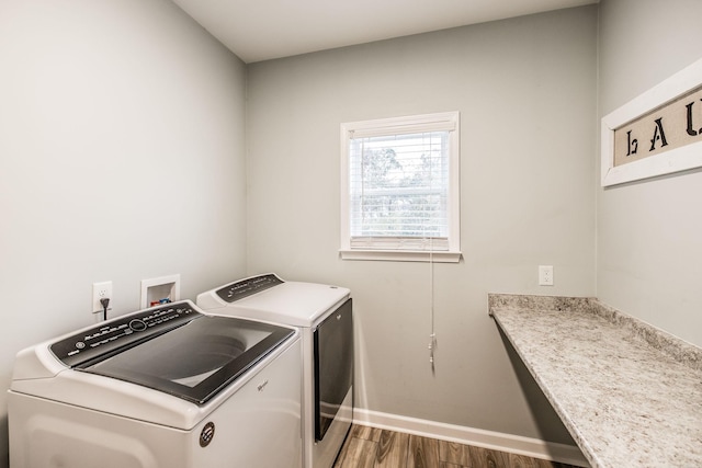 clothes washing area with separate washer and dryer and wood-type flooring