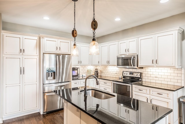 kitchen featuring pendant lighting, sink, white cabinets, decorative backsplash, and stainless steel appliances