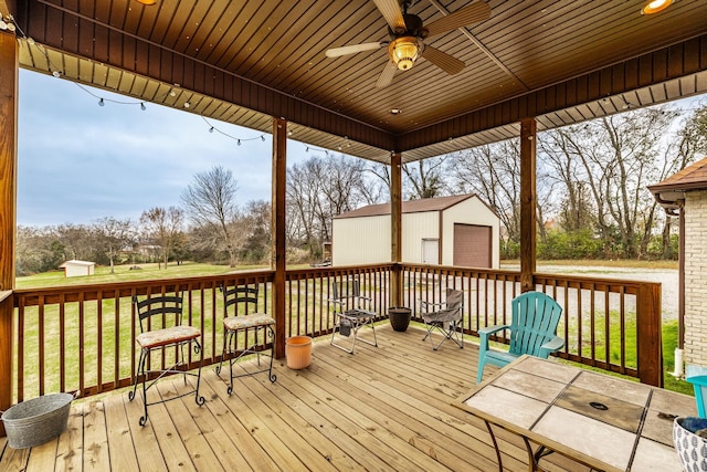 wooden terrace with a storage shed, a garage, a lawn, and ceiling fan