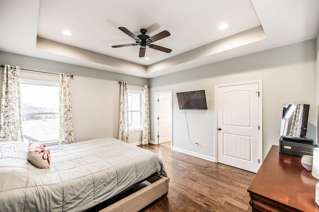 bedroom featuring dark wood-type flooring, ceiling fan, and a tray ceiling