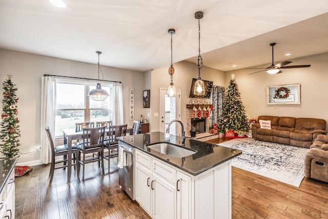 kitchen with dark stone countertops, dishwasher, pendant lighting, a kitchen island with sink, and white cabinets