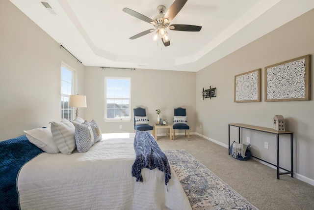 carpeted bedroom featuring a raised ceiling and ceiling fan