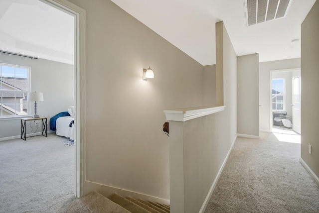 hallway featuring light carpet, vaulted ceiling, and a wealth of natural light