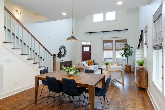 dining space featuring a towering ceiling and dark hardwood / wood-style flooring