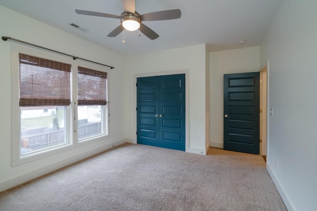 unfurnished bedroom featuring light carpet, a closet, and ceiling fan