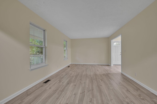 spare room with light wood-type flooring and a textured ceiling